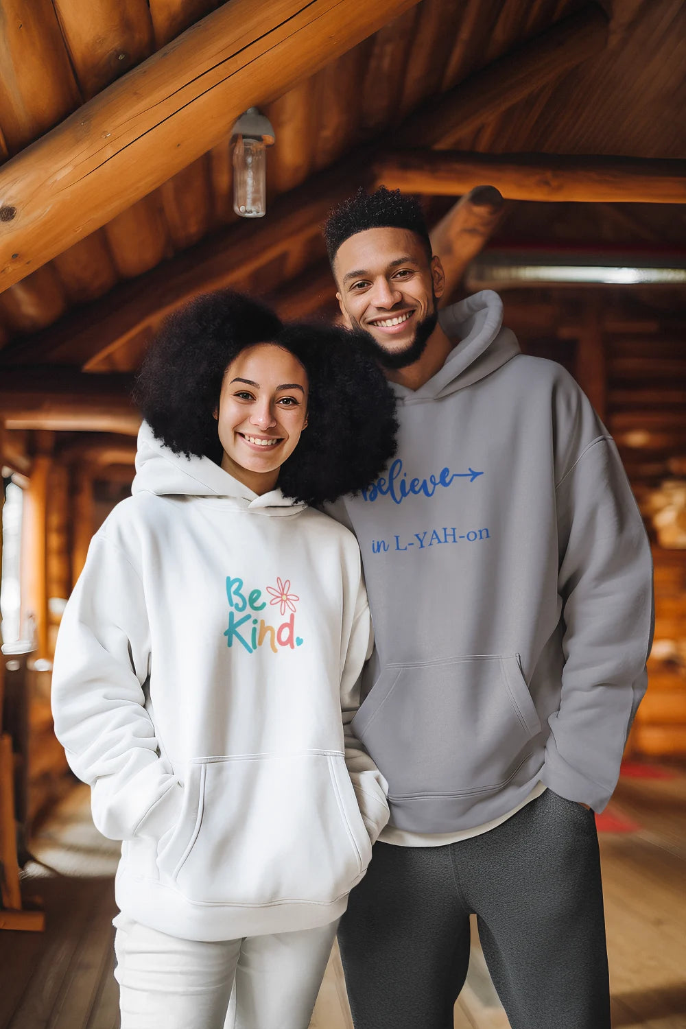 Two people wearing hoodies with motivational phrases indoors.