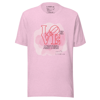 A pink crew neck t-shirt with the text 'LOVE ONE ANOTHER' printed in the center.