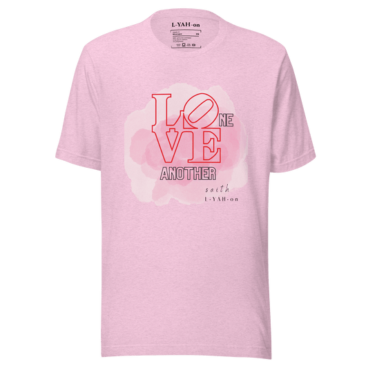 A pink crew neck t-shirt with the text 'LOVE ONE ANOTHER' printed in the center.